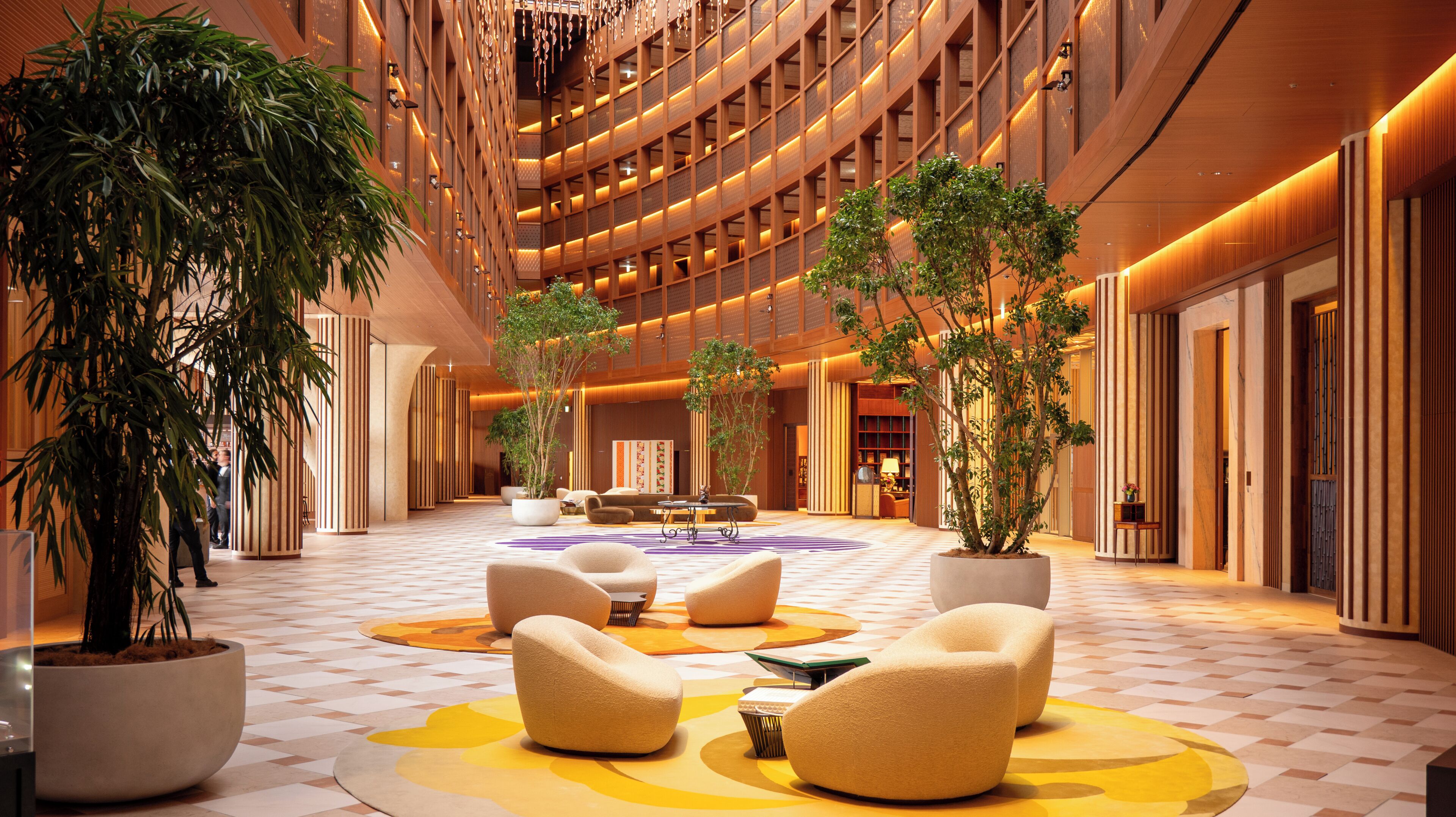 A spacious lobby with a checkered floor, seating areas, and potted plants.