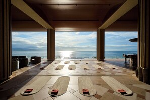 A spacious indoor area with a view of the sea, featuring a pool with lounge chairs and a bar area. - THE PASONA natureverse retreat (Awaji)
