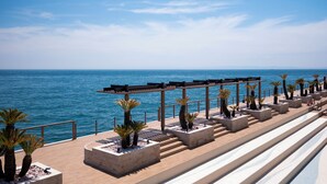 A seaside promenade with a wooden pergola, palm trees, and a view of the ocean. - THE PASONA natureverse retreat (Awaji)