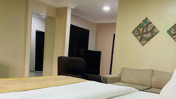 A hotel room with a bed, a sofa, a television, and a wall-mounted artwork. - Sienna Suites (Abuja)