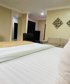 A hotel room with a bed, a sofa, a television, and a wall-mounted artwork. - Sienna Suites (Abuja)