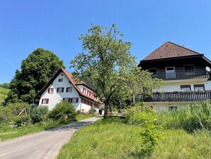 A rural road leading to a traditional white house with red shutters and a balcony. - Holiday Apartment 'Köpfle' with Mountain View, Shared Garden, and Wi-Fi (Glottertal)