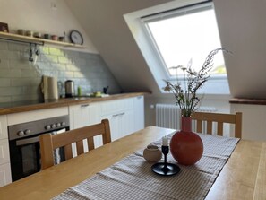 A kitchen with a dining table, a vase with flowers, and a window. - Holiday Apartment 'Köpfle' with Mountain View, Shared Garden, and Wi-Fi (Glottertal)