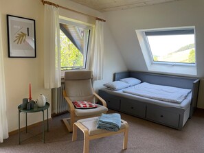 A bedroom with a bed, a chair, a small table, and a window with a view. - Holiday Apartment 'Köpfle' with Mountain View, Shared Garden, and Wi-Fi (Glottertal)