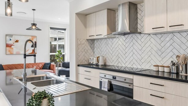Una cocina moderna con una isla central, electrodomésticos de acero inoxidable y un salpicadero de baldosas en espiga.