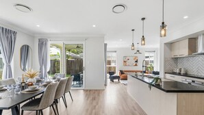 Cocina moderna con una isla central, iluminación colgante y vista al patio trasero.
