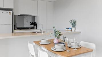 A modern kitchen with white cabinets, a wooden dining table, and a small island with a sink.