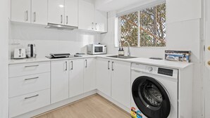 A modern kitchen with white cabinets, a microwave, a toaster, and a washing machine. - Self-Contained Studio | Perfect for Solo Travelers (MacGregor)