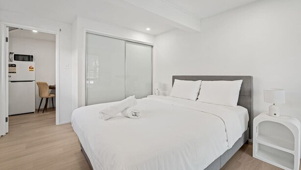Een moderne hotelkamer met een groot bed, een bureau en een kledingkast.