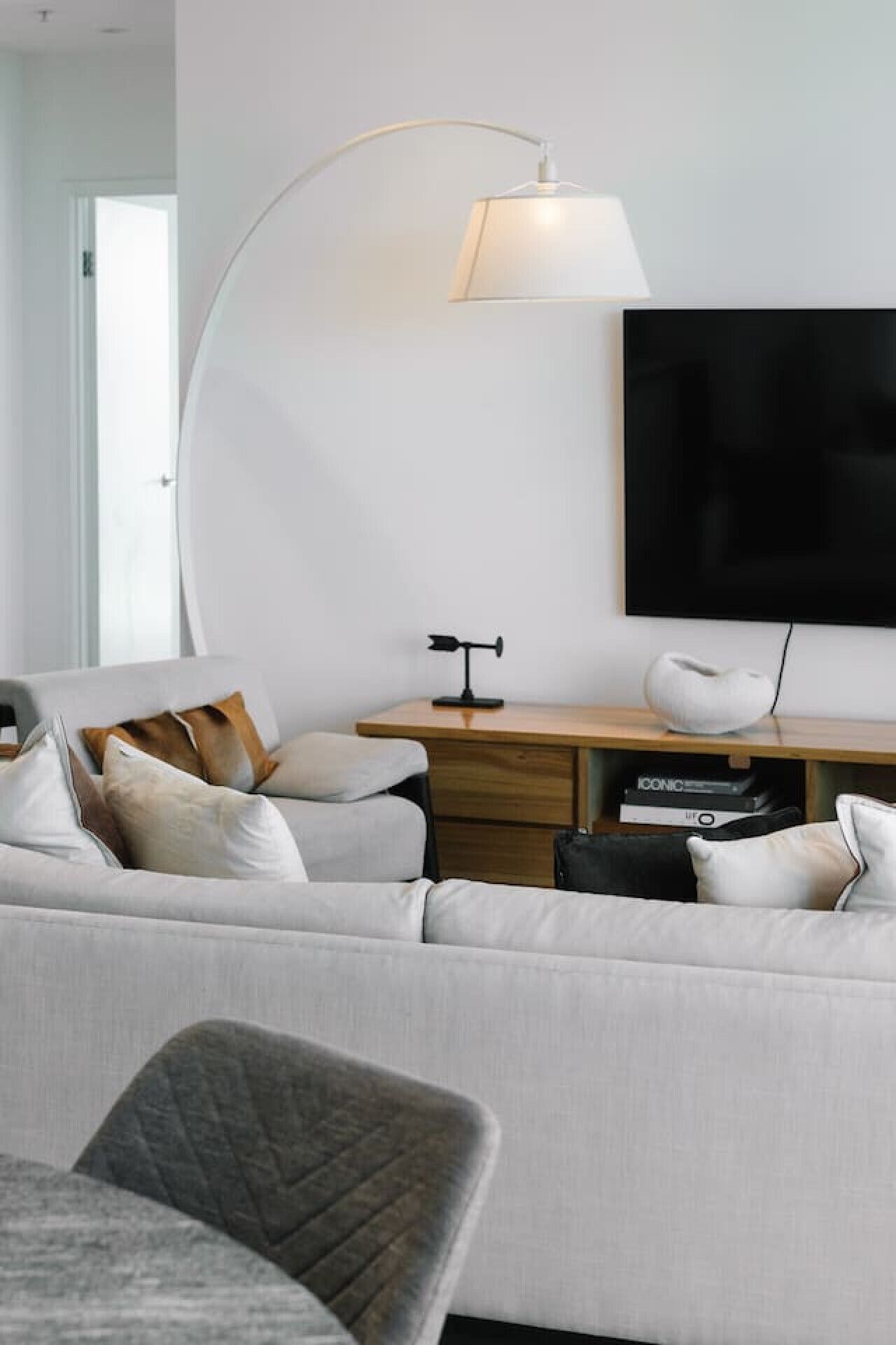 Un salon moderne comprenant un canapé, une table basse, un bureau avec une lampe et un téléviseur à écran plat fixé au mur.