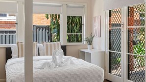 Habitación de hotel con una cama grande, una mesita de noche pequeña, una ventana con vistas a zonas verdes y una puerta corredera de vidrio.