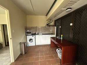 A compact kitchen with a washing machine, a microwave, and a sink. - Cozy 1BR Flat in Sunnybank | Solo&Couple Travelers (Sunnybank)