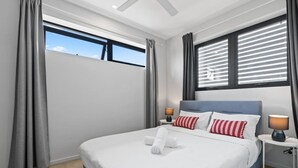 Habitación de hotel moderna con una cama grande, dos lámparas de noche y vista al cielo a través de las ventanas.