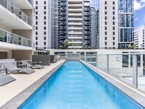 A rooftop swimming pool with lounge chairs and a depth sign. - Prime CBD Stay | Walk to Queen St Mall | 1 Parking (Brisbane City)