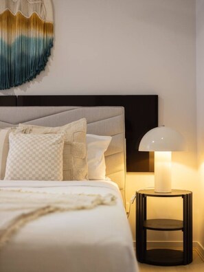 Un lit bien fait, avec un oreiller à carreaux, une lampe de chevet et un élément décoratif fixé au mur.