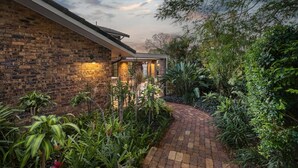 Een stenen huis met een tuinpad dat leidt naar een overdekt gedeelte.