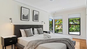 Een moderne slaapkamer met een groot bed, een nachtkastje, een bedlampje en twee ingelijste foto's aan de muur.