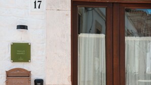 A wooden door with a glass panel, a mailbox, and a house number '17' on a white wall. - TRULLO MAMELI - DIEMME STAY (Alberobello)