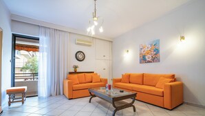 A living room with two orange sofas, a wooden coffee table, a clock, and a painting on the wall. - Authentic Athens stay in Kypseli by ΜΡS (Athina)