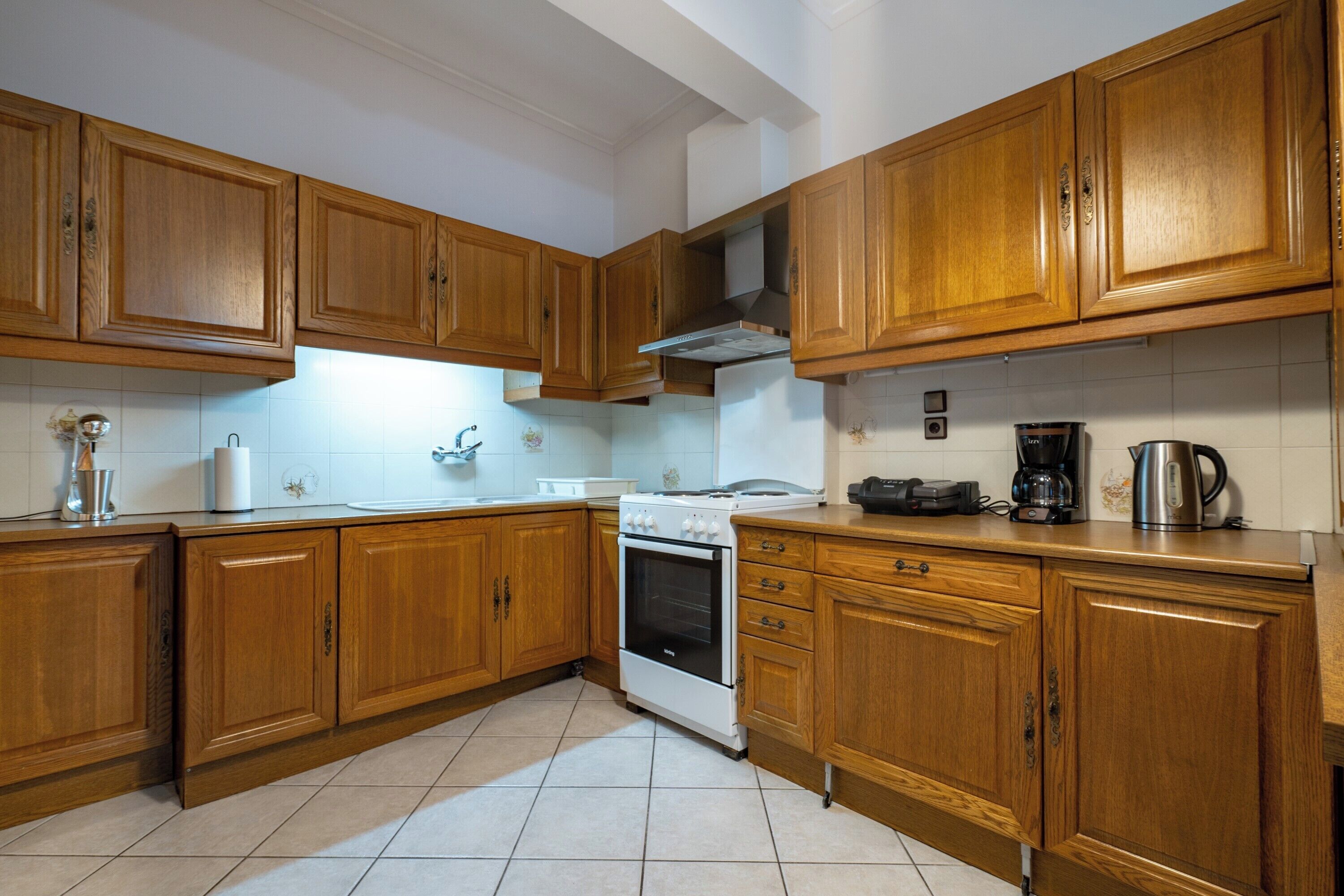 Una cocina con armarios de madera, una estufa blanca y una cafetera.