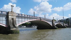 Un ponte con un arco decorativo e una statua a sinistra.