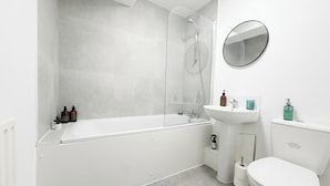 Un bagno moderno con una vasca, un lavandino, un water e uno specchio.