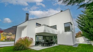 Une maison moderne à deux étages, dotée d’un toit plat, de grandes fenêtres et d’une pelouse bien entretenue.