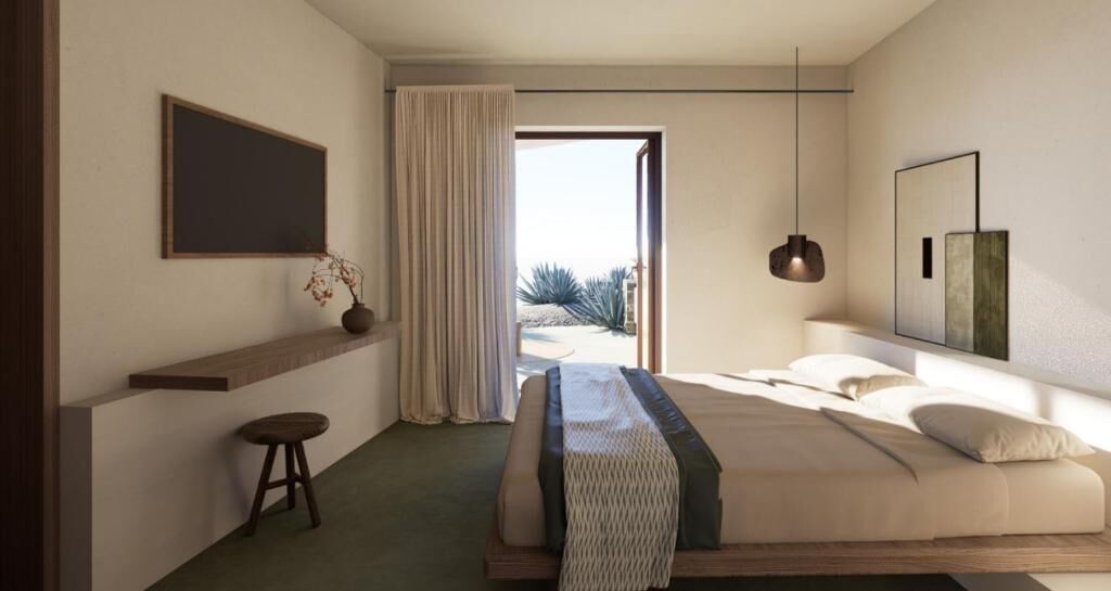 Une chambre à coucher avec un lit, un petit tabouret, une plante en pot, un tableau et une vue sur l’extérieur.