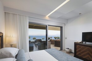 Ein Hotelzimmer mit Bett, Fernseher, Balkon mit Sitzgelegenheit und Meerblick.