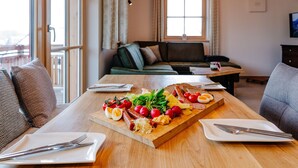 Et spisebord med forskellige spisemuligheder, herunder æg, tomater og ost, placeret i et rum med en sofa og et fjernsyn.