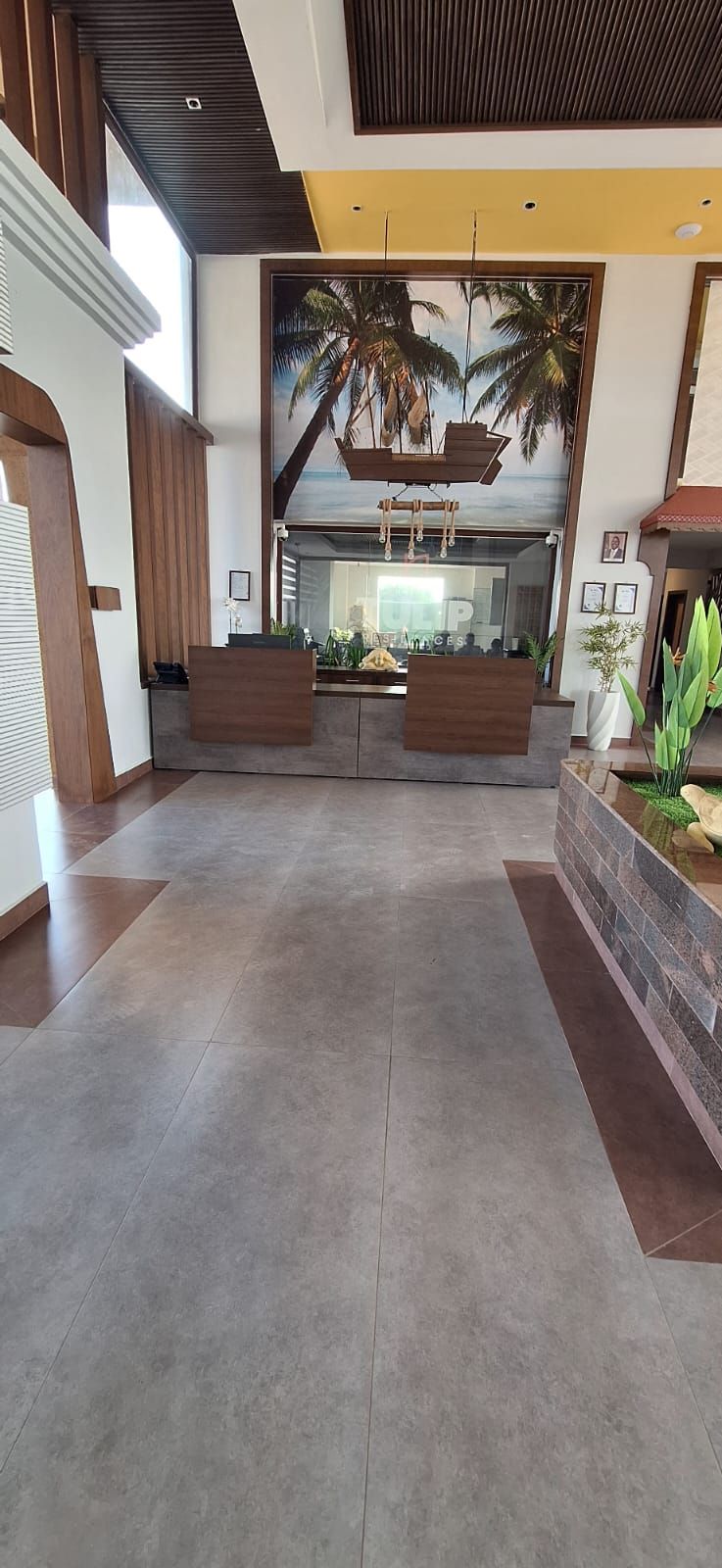 Een receptiegedeelte met een modern design, met een receptiebalie, zithoek en een groot raam met uitzicht op palmbomen.