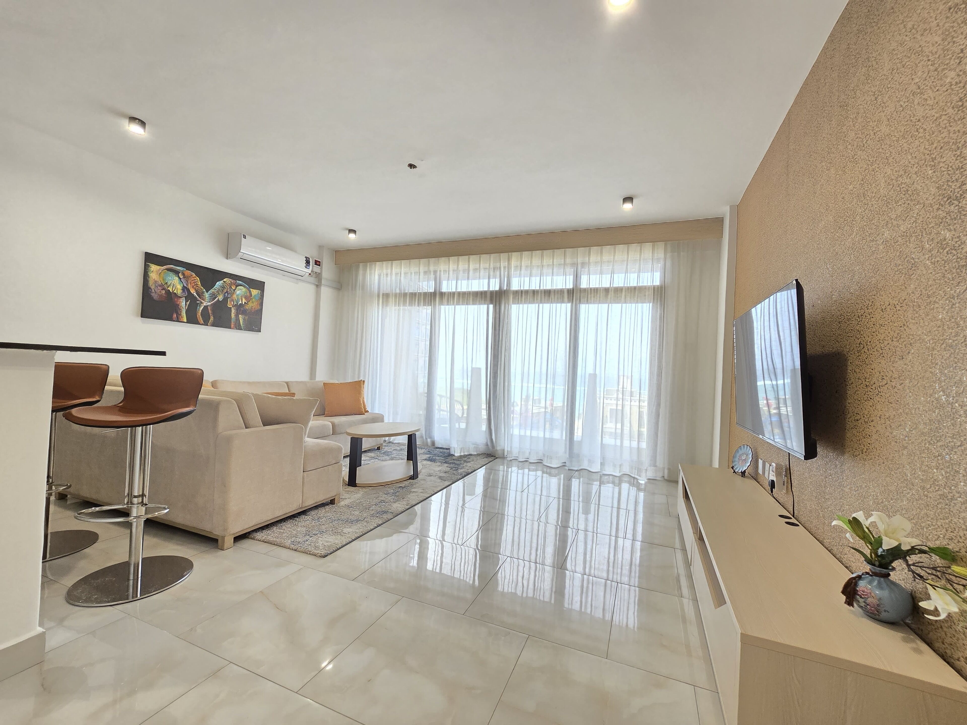 A modern living room with a sofa, coffee table, and a TV mounted on the wall.