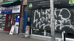 Um edifício com várias lojas, incluindo uma assistência técnica de celulares e uma funerária.