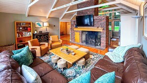 Ein gemütliches Wohnzimmer mit Kamin, Ledersofas, einem Couchtisch und einem Bücherregal.