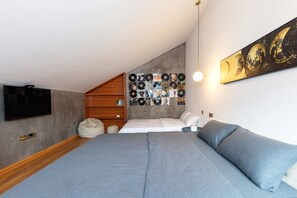 A bedroom with a bed, a wall-mounted TV, a record collection, and a painting. - Comfortable Air-Conditioned 2-Bedroom Apartment/Loft with Easy Park Access (Zhangjiajie)