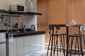 A modern kitchen with a microwave, stove, and bar stools.