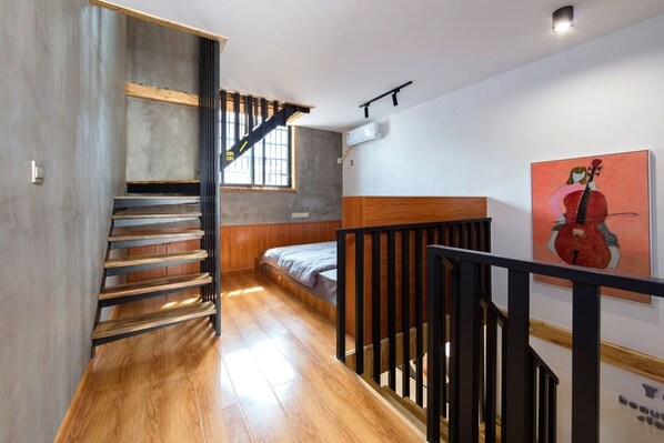 A staircase leading to a bedroom with a bunk bed, a wooden floor, and a painting on the wall.