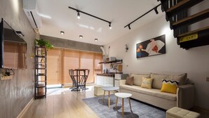 A modern living room with a sofa, coffee table, and a dining area with a table and chairs.