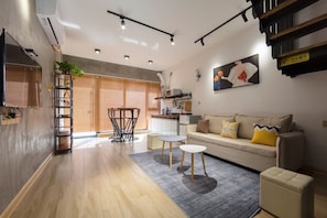 A modern living room with a sofa, coffee table, and a dining area with a table and chairs.