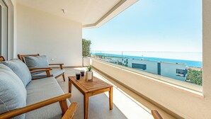 A balcony with a sofa, wooden table, and a view of the sea. - Apartments Twins with private pool  (Novalja)
