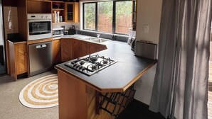 Una cucina compatta con mobili in legno, un piano cottura a gas, un forno a microonde e un lavello.