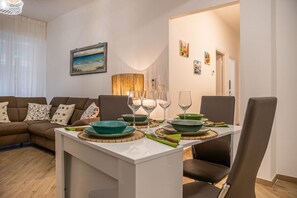 Ein Essbereich mit Tisch für vier Personen, einer Couch und einem Gemälde an der Wand.
