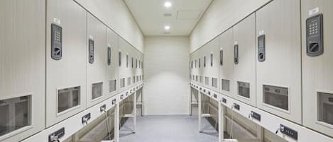 A row of lockers with numbered labels, a tiled floor, and a ceiling with recessed lighting.