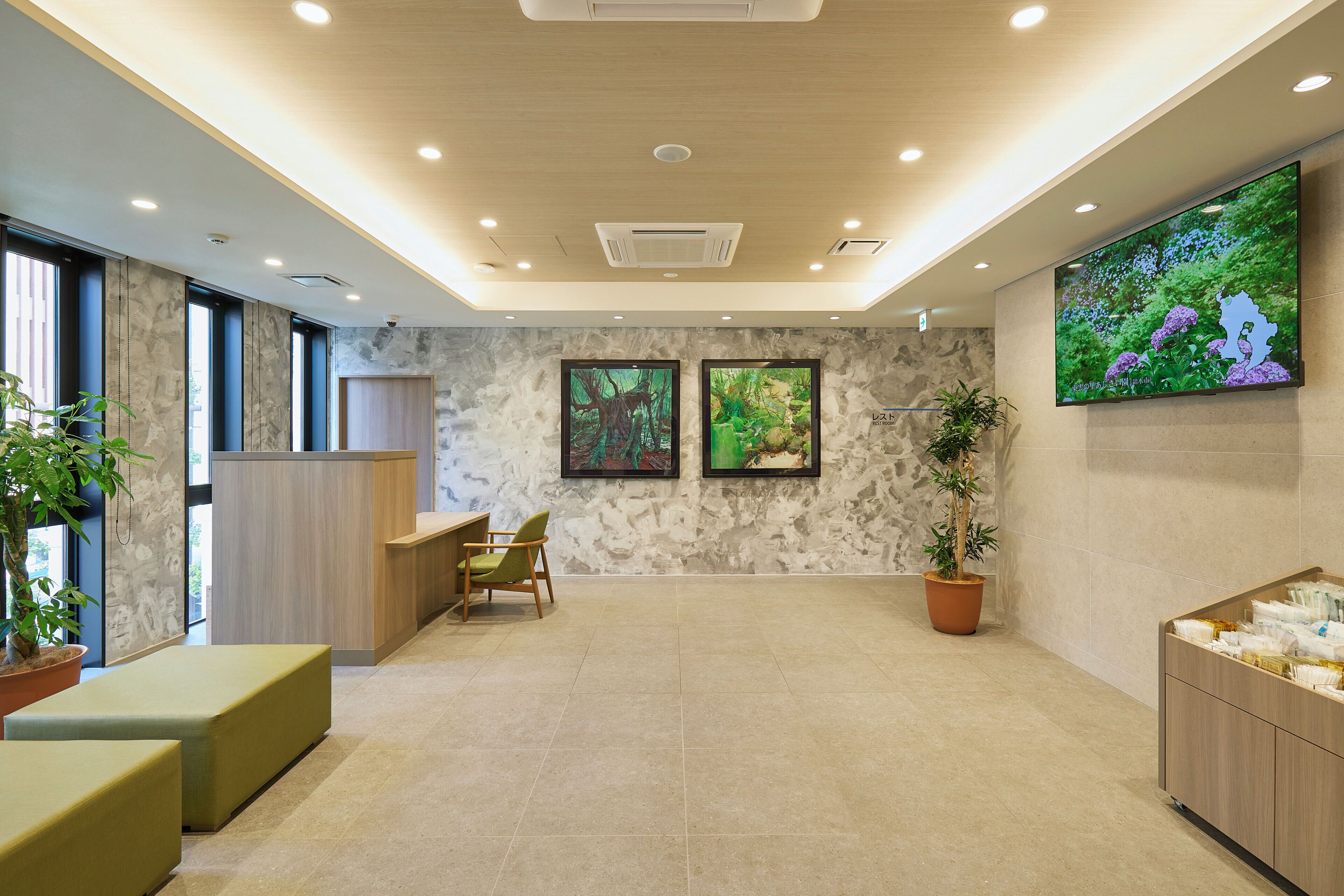 A modern lobby with a reception desk, seating area, and a large screen displaying nature.