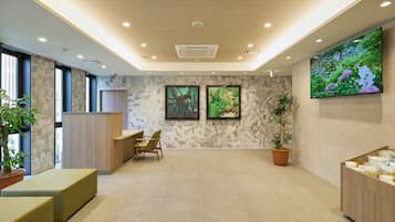 A modern lobby with a reception desk, seating area, and a large screen displaying nature.