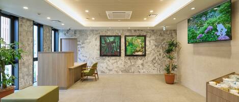 A modern lobby with a reception desk, seating area, and a large screen displaying nature.