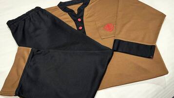 Una camisa negra y marrón con un logotipo rojo en el bolsillo.