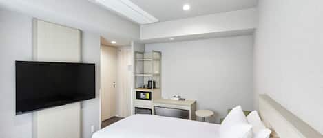 A hotel room with a bed, a desk, a chair, a television, and a wardrobe.