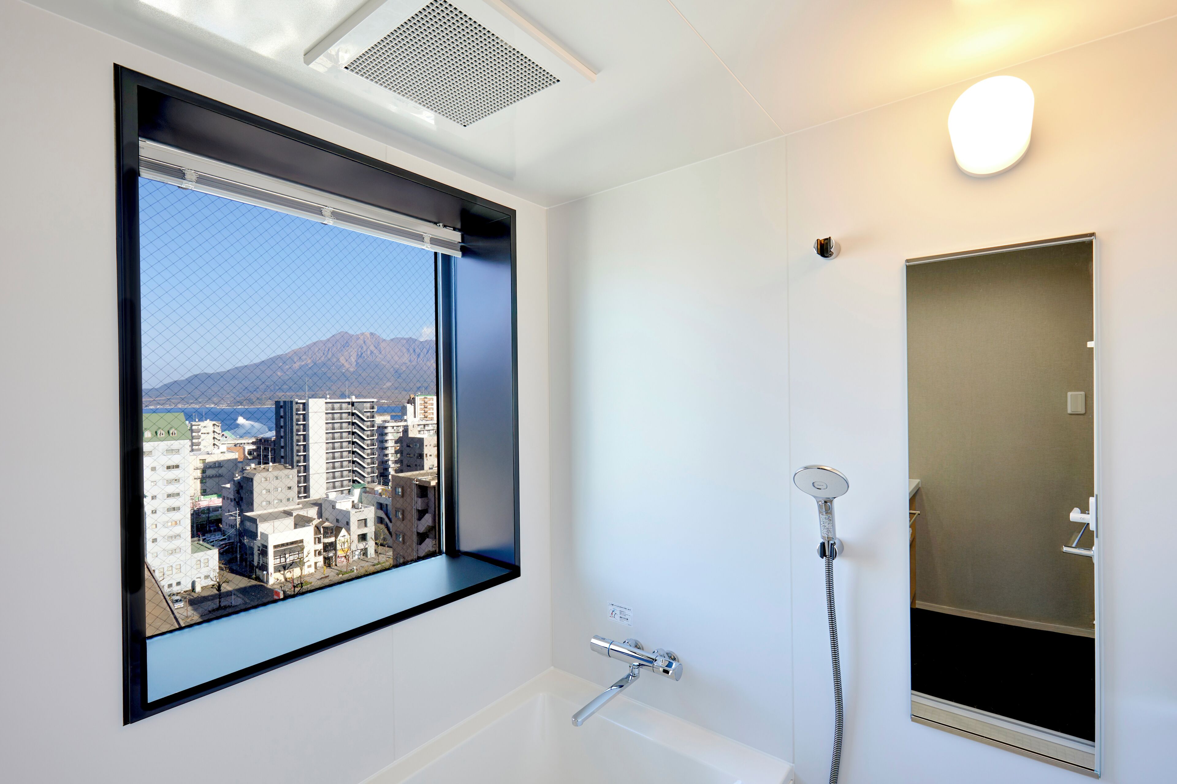 Ein modernes Badezimmer mit großem Fenster, einer Badewanne und einer Dusche.