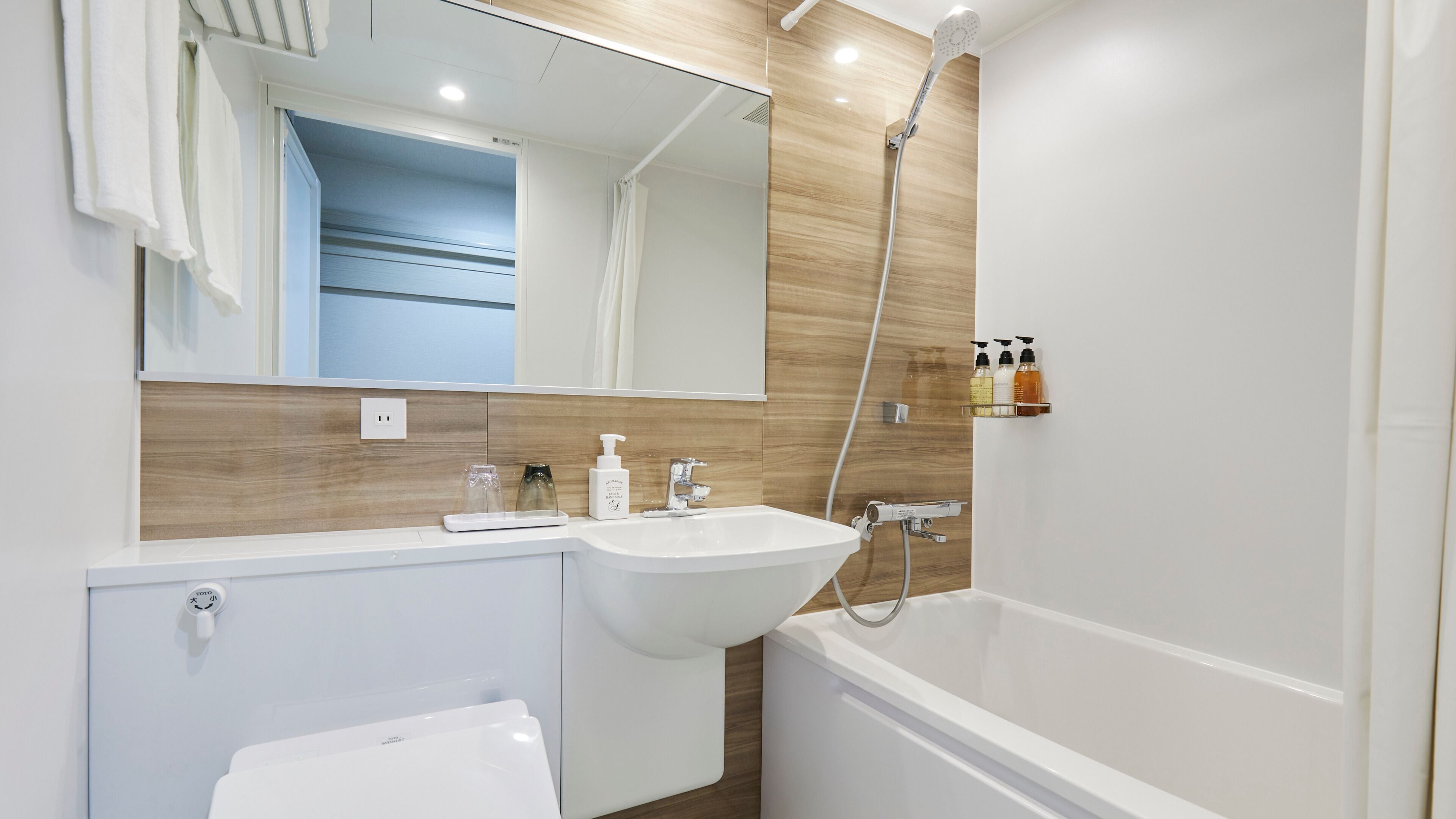 Een moderne badkamer met een wastafel, spiegel, douche en toiletartikelen.